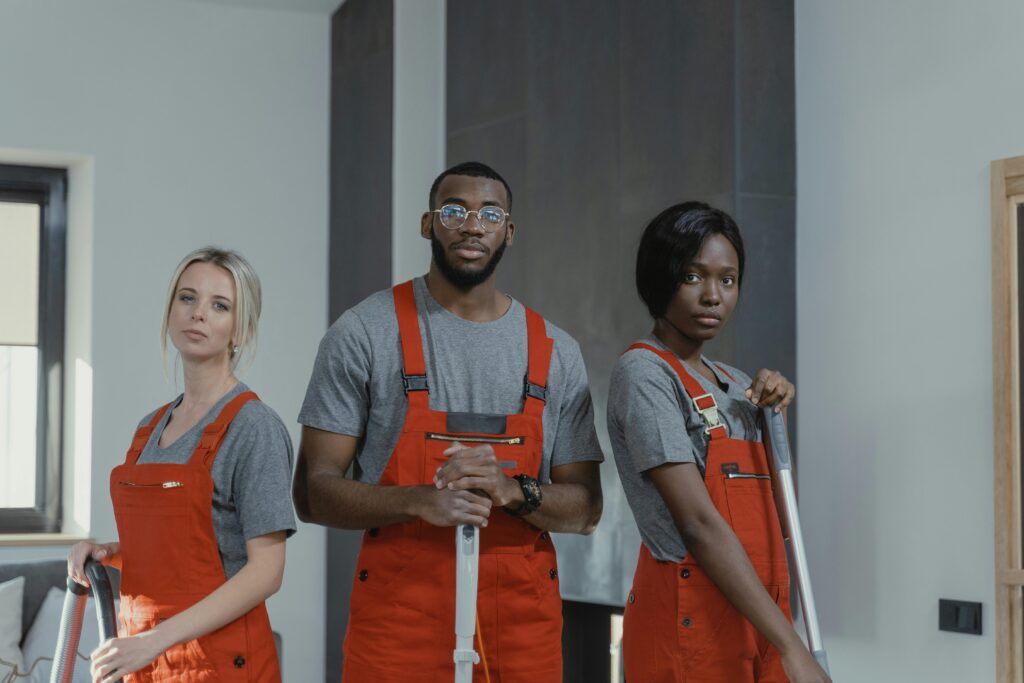 A diverse team of cleaning professionals in uniform posing in an indoor setting.